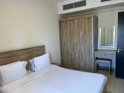 a bedroom with a white bed and a wooden cabinet at Jomana Aldau Heights Hurghada rent one bedroom apartment in Hurghada