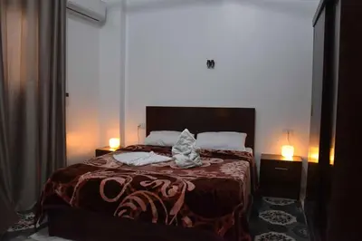 a bedroom with a bed with two lamps on it at Amenirdis Villa in Al Qurnah