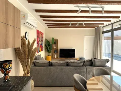 a living room with a gray couch and a tv at Unique 2BR Villa - Private Pool In Bali-ElGouna in El Gouna