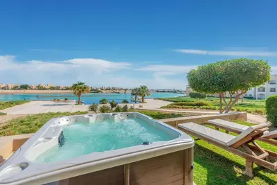 a hot tub in a garden with a view of the water at Gouna Retreat 2BR Apt Waterside Hot Tub & Pool in Hurghada