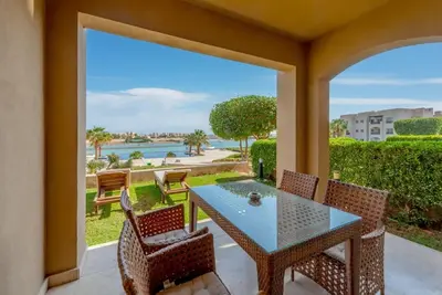 a patio with a table and chairs and a view of the ocean at Gouna Retreat 2BR Apt Waterside Hot Tub & Pool in Hurghada
