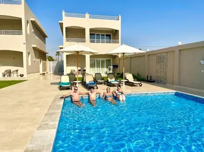 a group of men in a swimming pool in front of a house at Royal Nile Suites - Nile View 1 in Luxor