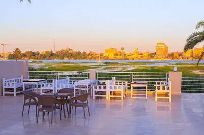 a patio with tables and chairs on a roof at Royal Nile Suites - Nile View 1 in Luxor