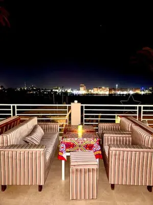 a deck with three couches and a table with a candle at Royal Nile Suites - Nile View 2 in Al Aqālitah