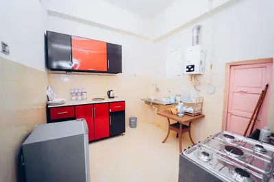 a small kitchen with red cabinets and a stove at Pharaoh apatrtment in Al Karnak