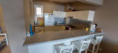 a kitchen with a counter top with a refrigerator and stools at Joubal lagoon Elgouna 2BD in Hurghada