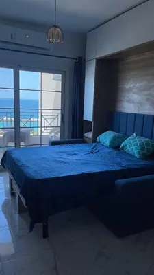 a bedroom with a blue bed with a view of the ocean at Luxurious and Cozy Seafront Studio Near Gouna in Hurghada