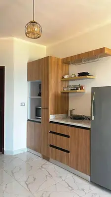 a kitchen with wooden cabinets and a stainless steel refrigerator at Luxurious and Cozy Seafront Studio Near Gouna in Hurghada