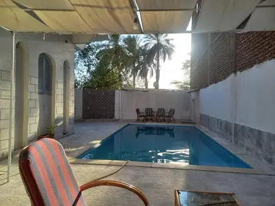 a swimming pool with a chair and a table at Villa Rose - Luxor in Luxor