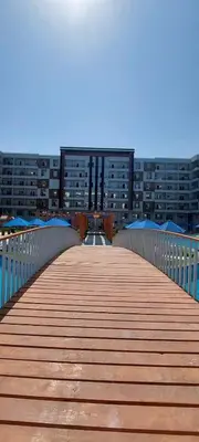 a wooden bridge with a building in the background at Tiba Golden Beach Resort, Down Town in Hurghada