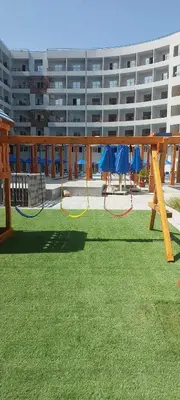 a park with swings in the grass in front of a building at Tiba Golden Beach Resort, Down Town in Hurghada