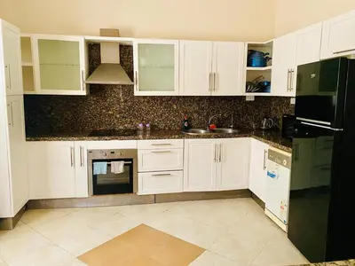 a kitchen with white cabinets and a black refrigerator at Magawish villa in the heart of the city in Hurghada