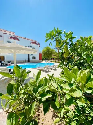 a resort with a pool and a white umbrella at Magawish villa in the heart of the city in Hurghada