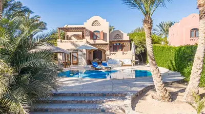 a villa with a swimming pool and palm trees at Cozy villa with private pool in Upper Nubia in Hurghada