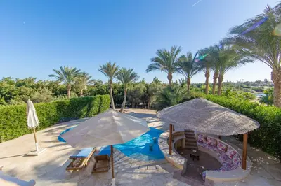 a patio with two umbrellas and a swimming pool at Cozy villa with private pool in Upper Nubia in Hurghada
