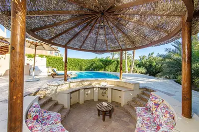 a patio with an umbrella and a swimming pool at Cozy villa with private pool in Upper Nubia in Hurghada