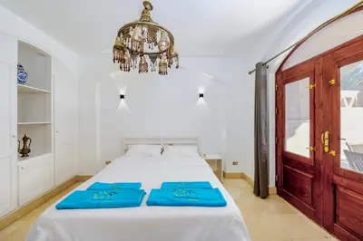 a bedroom with a bed with blue sheets and a chandelier at Cozy villa with private pool in Upper Nubia in Hurghada