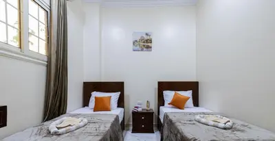 two beds in a room with white walls and windows at Samara Guest House in Aswan