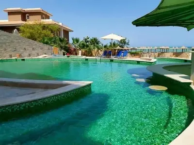 a swimming pool with turquoise water at Turtles Beach resort hourghada Studio view sea view pool private beach jacuzzi pools air-conditioned restaurant on the beach jacuzzi security and a large sunny balcony in Hurghada