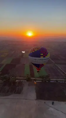 a hot air balloon flying over a field with the sunset at Nile Cruise 2 nights 3 Days From Aswan to Luxor with tours in Aswan