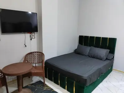 a bedroom with a bed and a table and a tv at Studio FOR RENT IN ELWAZRA EREA BEFOR EL GOUNA 5 MINUTES ONE BEDROOM in Hurghada