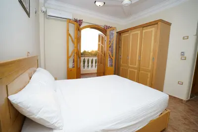 a bedroom with a white bed and an open door at Morning Star Apartment in Luxor