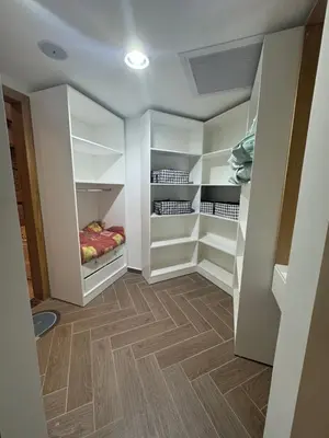 a walk in closet with white cabinets and wood floors at Luxury Smart Home- Villa Duplex in Hurghada