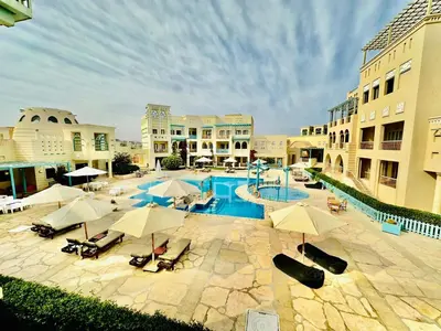 an outdoor swimming pool with umbrellas and chairs and buildings at Gouna Luxuy Condo Hotel in El Gouna