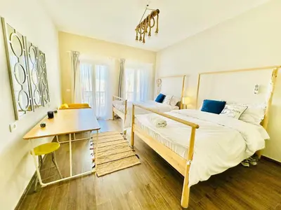 a bedroom with two beds and a table and a desk at Gouna Luxuy Condo Hotel in El Gouna