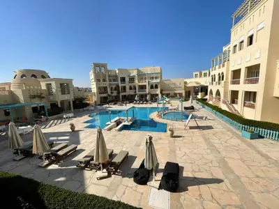 a swimming pool with chairs and umbrellas in a resort at Gouna Luxuy Condo Hotel in El Gouna
