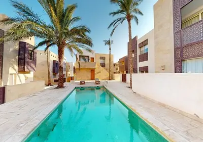 a swimming pool with palm trees and a building at Cozy 2 Bedroom-WS3 at SCARAB Elgouna in Hurghada