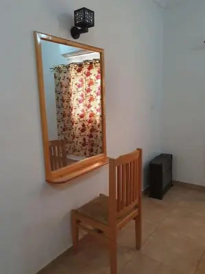 a mirror on a wall next to a wooden chair at Sekhmet Appartement 3 chambres in Luxor