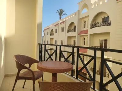 a balcony with a table and chairs and a building at Palm Beach Piazza Beachfront lovely Apartment in Hurghada