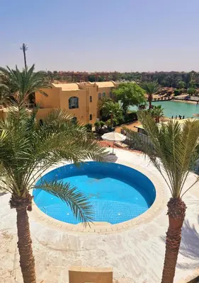 a pool with palm trees in front of a resort at Lovely1 Bedroom Downtown ELGouna F04 in Hurghada