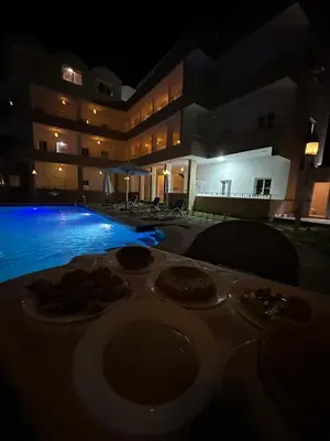 a table with plates of food next to a swimming pool at siriuspalaceluxor in Al Karnak
