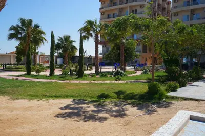 a park with palm trees and a building at Casablanca Beach - Panoramic Sea view Apartment in Hurghada