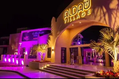 a man standing outside of a building with purple lights at Aldau Heights Apartment in Hurghada