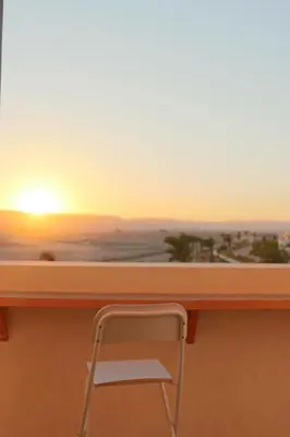 a desk with a chair in front of a sunset at Sunrise to Sunset Rooftop Panorama - El Gouna Shedwan in Hurghada