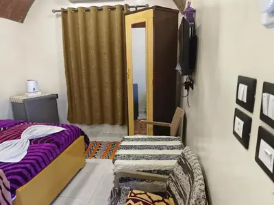 a bedroom with a bed and a chair and a door at Lale Hoste in Nag` el-Ramla
