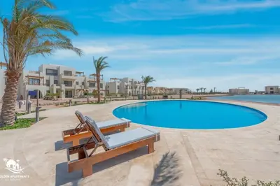 a swimming pool with a bench and some palm trees at Tranquil 2BR in Shedwan I El Gouna I Pool and Lagoon View in Hurghada