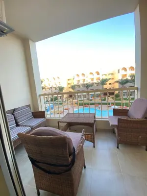 a balcony with chairs and tables and a swimming pool at Apartment in el karma aqua beach resort hurghada near el gouna 3 in Hurghada
