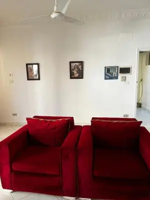 a red couch in a living room with pictures on the wall at Sekhmet Appartement 2 chambres in Luxor