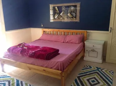 a bedroom with a bed with a purple comforter at Luxor Stables Apartment in Luxor