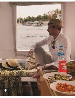 a man sitting on a boat with plates of food at faloka Farha Camp in Aswan