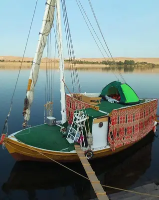 a sail boat with a tent on the water at faloka Farha Camp in Aswan