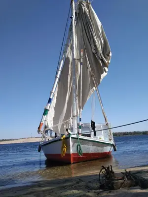 a sail boat sitting in the water on the beach at faloka Farha Camp in Aswan