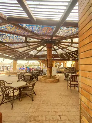 a patio with tables and chairs under a roof at Lux Gardenhouse pool WiFi Private garden Hurghada in Hurghada