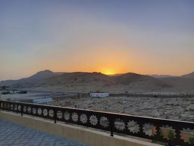 a sunset over a desert with mountains in the background at Carter Guesthouse Luxor 1 in ‘Ezbet Abu Ḥabashi