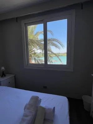 a bedroom with a window and a palm tree at The Sunset Heaven - 2 bedrooms - Golf Steigenberger, El Gouna in Hurghada