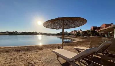 a couple of chairs and an umbrella on a beach at The Sunset Heaven - 2 bedrooms - Golf Steigenberger, El Gouna in Hurghada